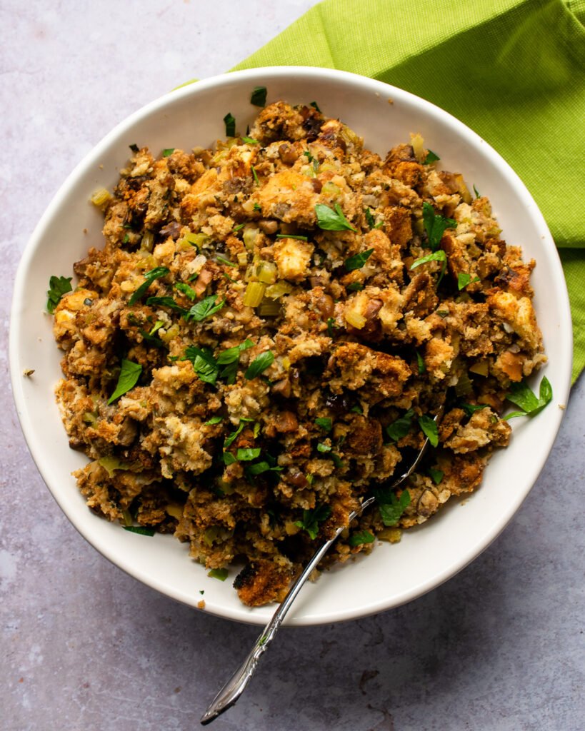 A bowl of Thanksgiving stuffing in a white bowl with a green napkin.