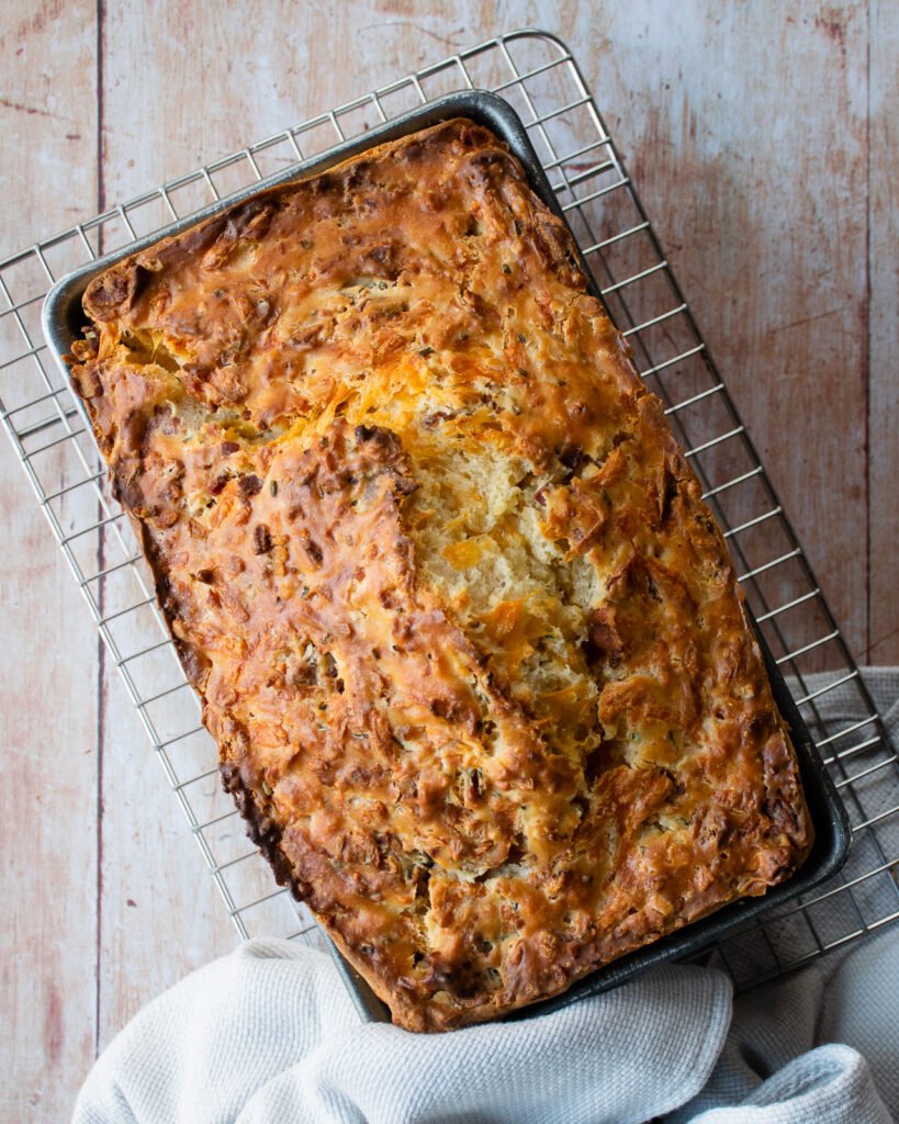 Buttermilk biscuit bread cooling on a rack on a wooden table.