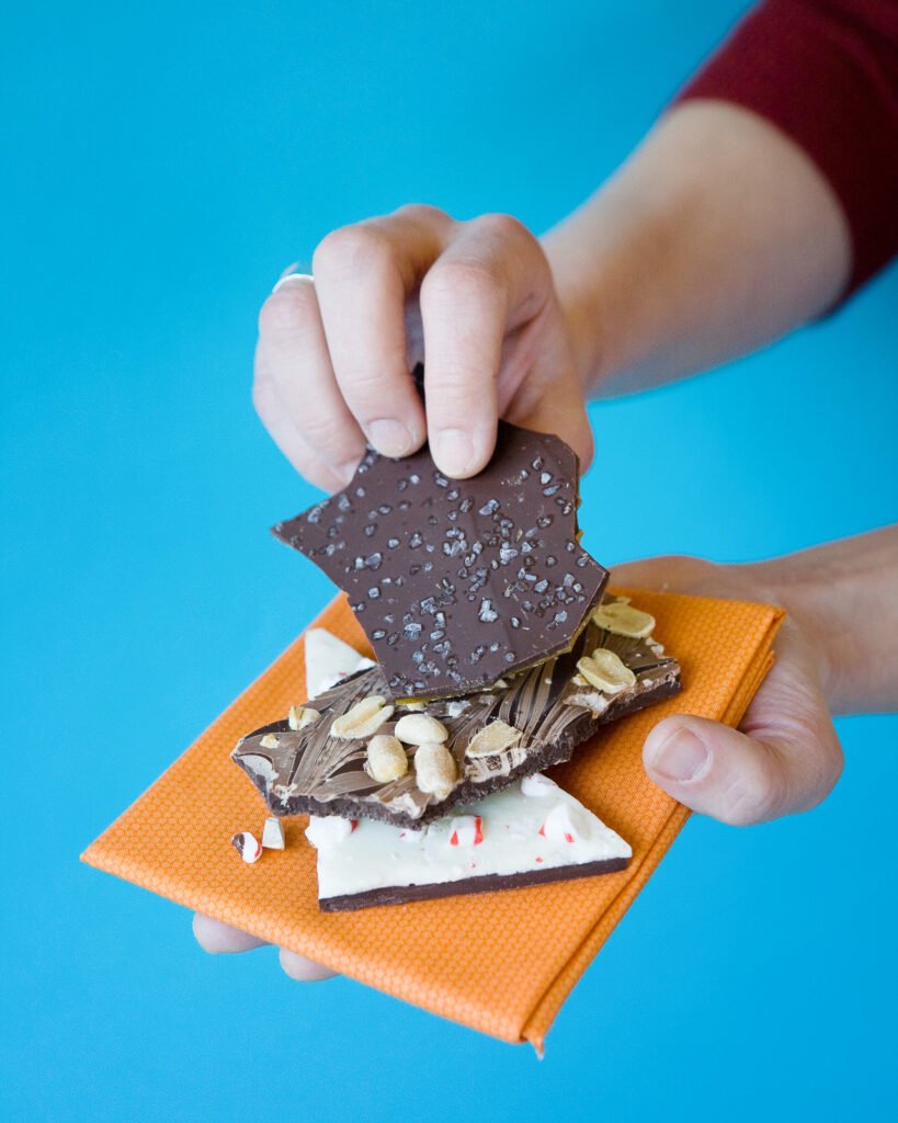 A hand holding several different types of bark on an orange napkin.