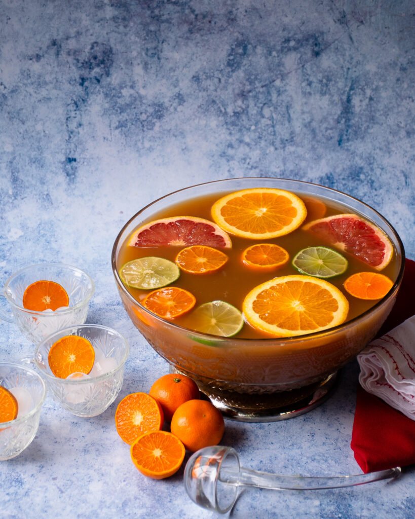 Punch in a punch bowl with slices of fruit and a ladle.
