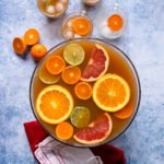 Tea punch in a punch bowl with grapefruit, orange, lime and mandarin slices floating in it.