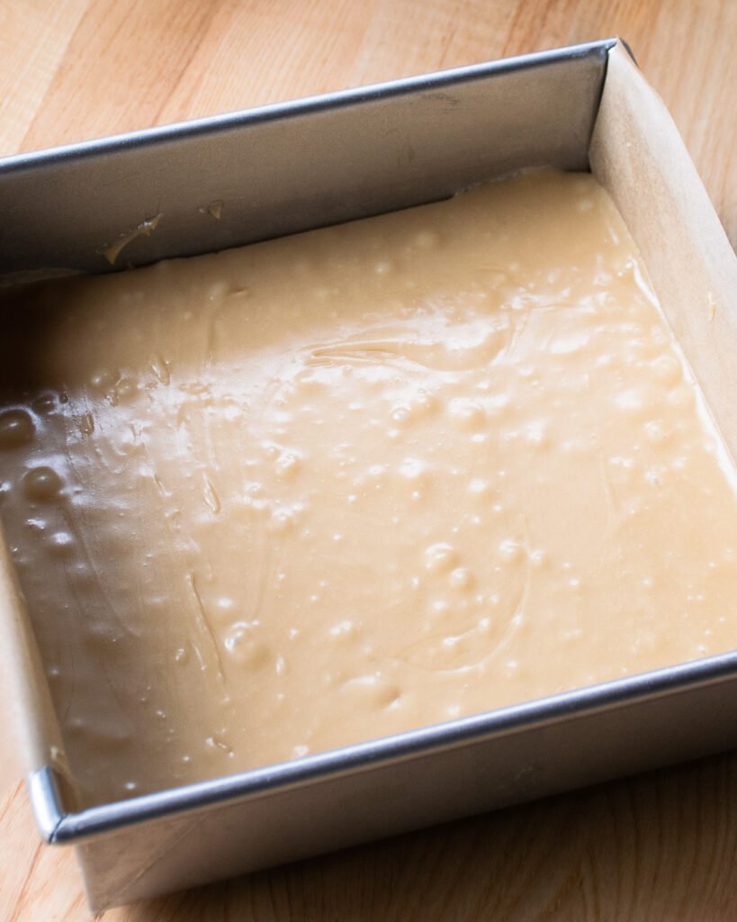 A square cake pan with sucre a la creme poured into it.