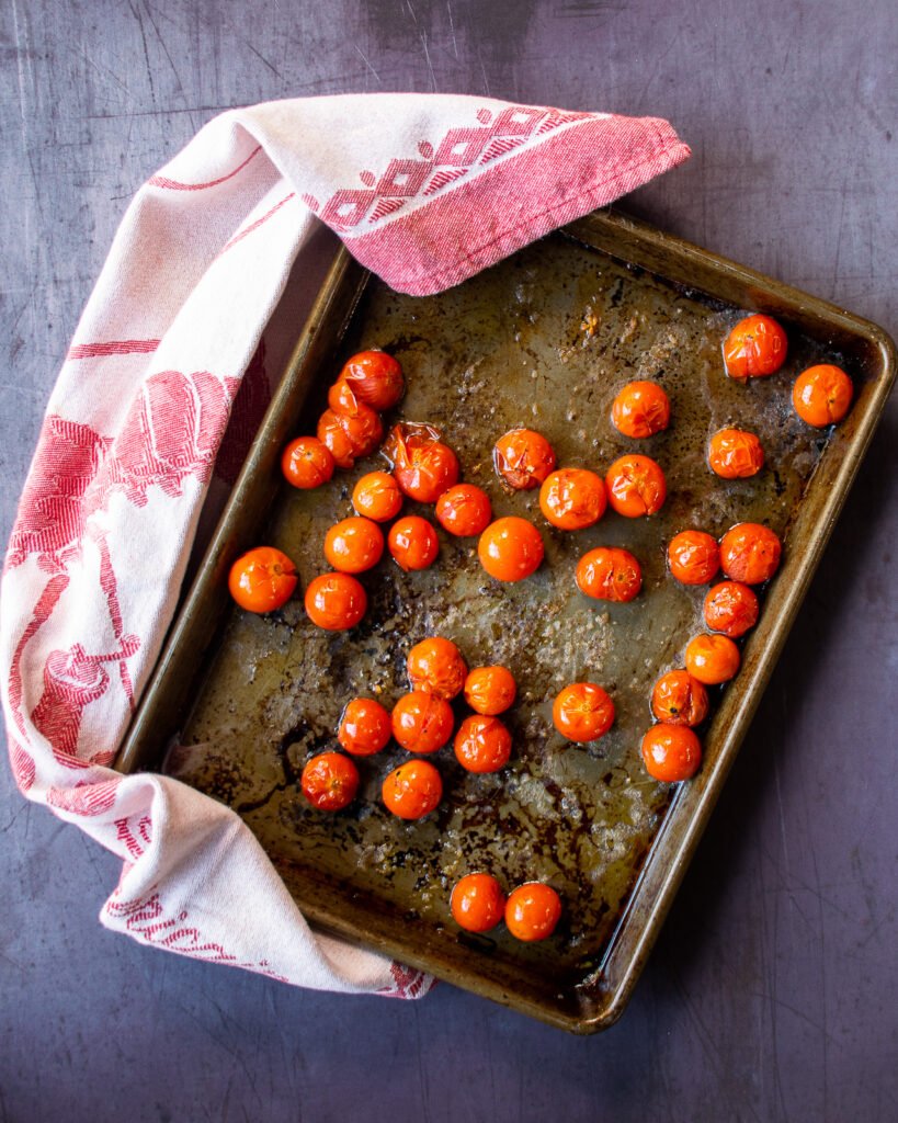 Cherry tomatoes on a baking sheet with a red towel.