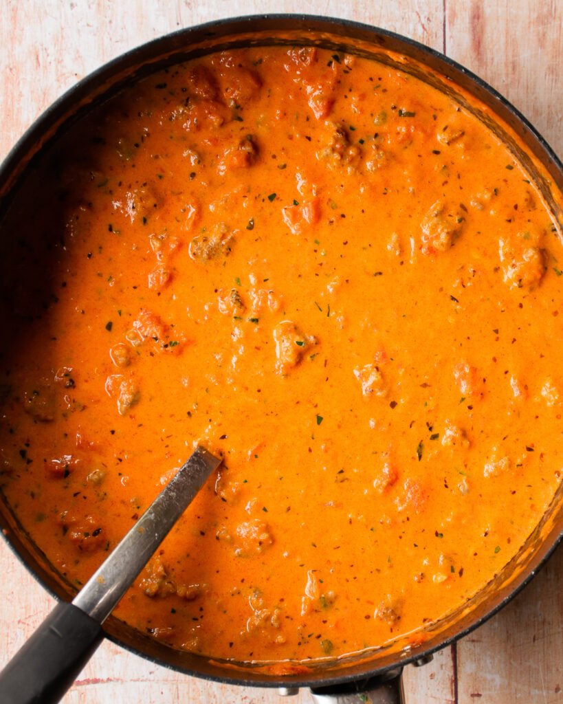 Creamy tomato sauce in a sauté pan with a spoon sticking out of it.