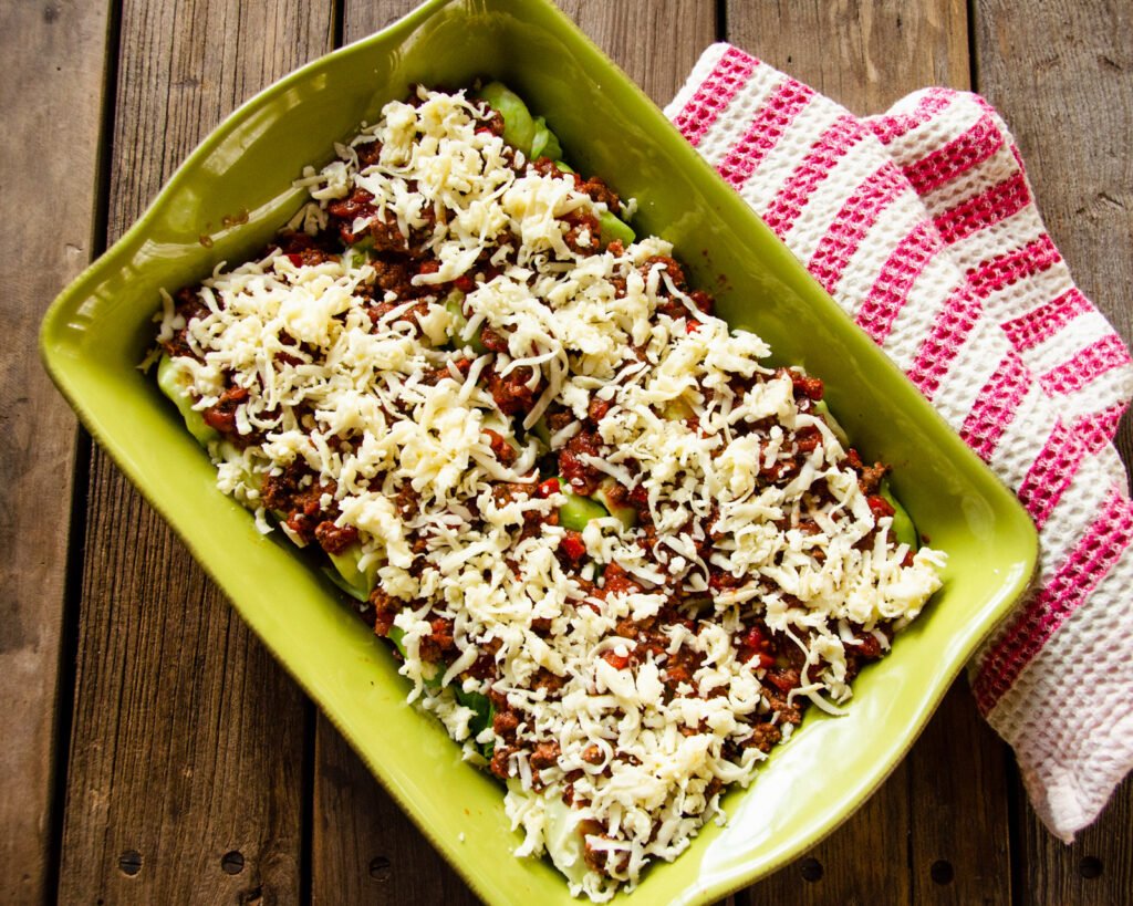 Ricotta Stuffed Cabbage Shells prepared in a ceramic casserole dish ready to go into the oven.