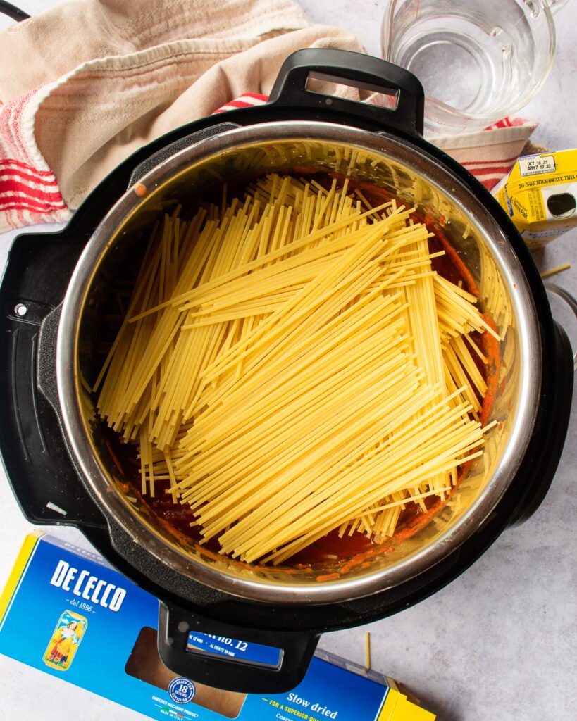 Pasta added to the top of a pressure cooker.