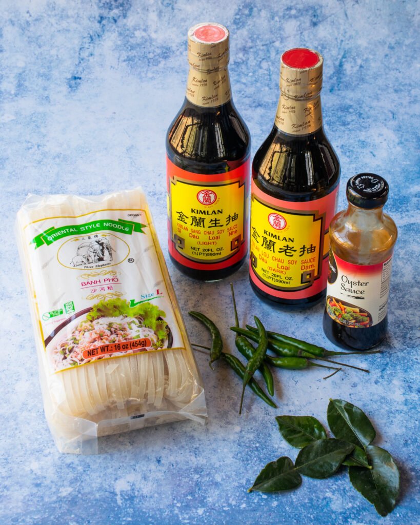 Ingredients for drunken noodles - dark and light soy sauce, oyster sauce, rice noodles, lime leaves and chili peppers.