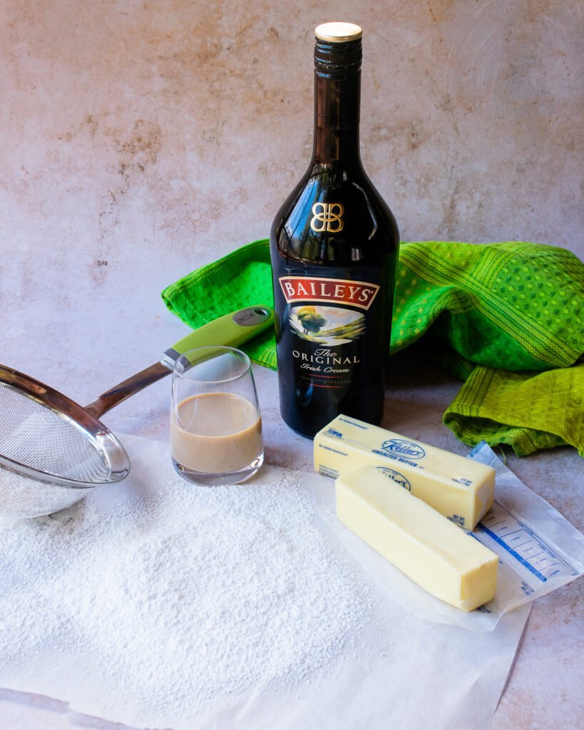 Ingredients for Irish cream frosting on a counter - powdered sugar, butter, and Bailey's Irish Cream.