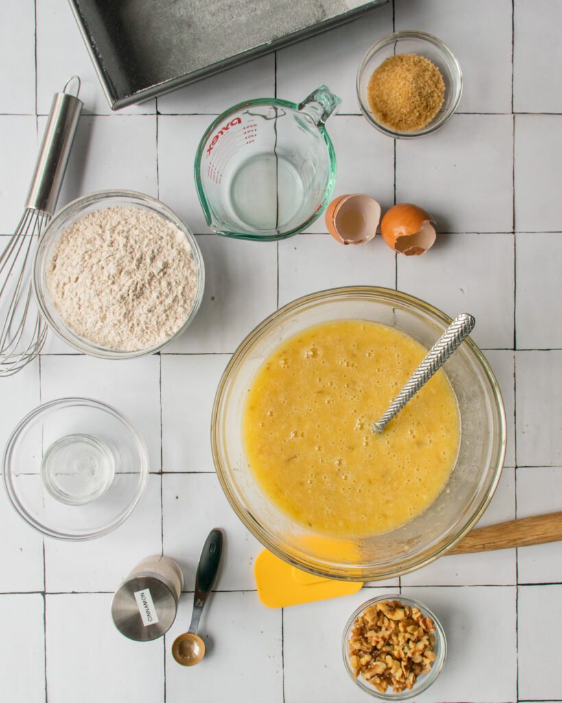 INgredients for banana bread on a countertop with a loaf pan.