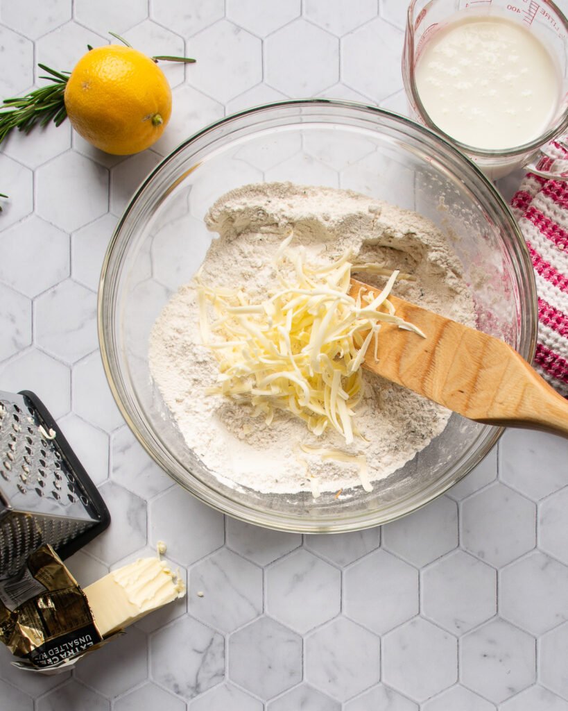 Butter grated into a bowl of flour with buttermilk and lemon nearby.
