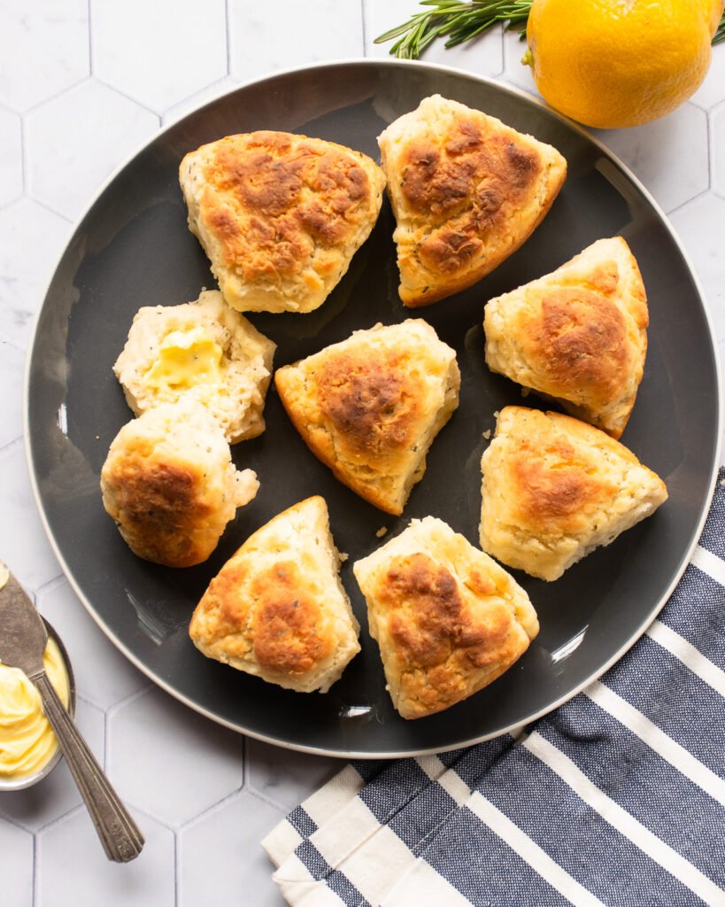 Lemon Rosemary biscuits on a grey plate with a grey and white towel and a little dish of butter.