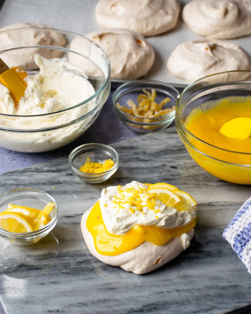Mini Lemon Pavlova Cloud on a marble surface with ingredients around.