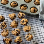 Blueberry Pup-Muffins on a cooling rack with more in a mini muffin pan in the background.