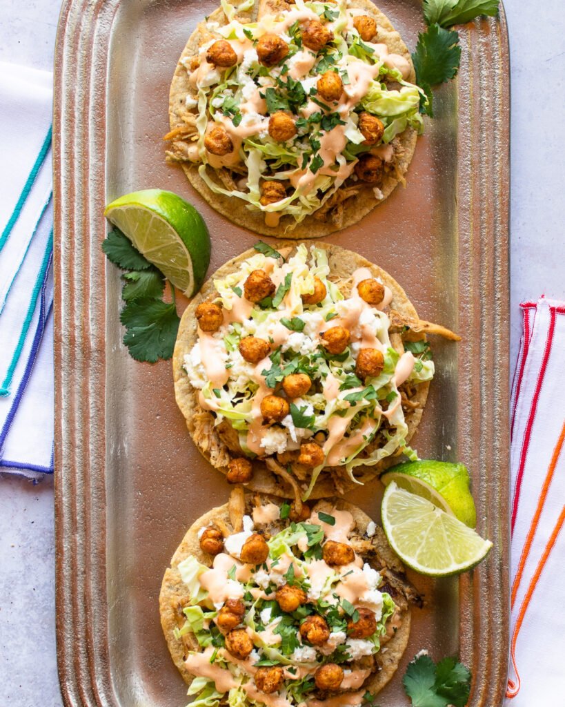 Three chicken tostadas on a silver platter.