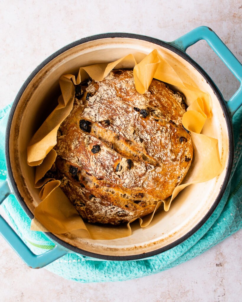 No knead fruit and nut bread in a turquoise Dutch oven.