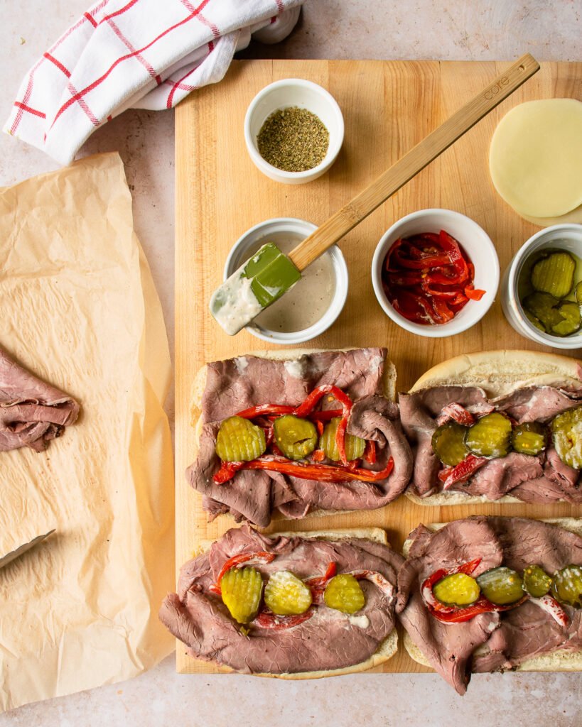 Assembling roast beef sandwiches with all the ingredients on a cutting board.
