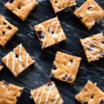 Blueberry blondies on a black marble surface.