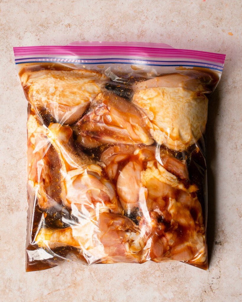 A zipper sealable plastic bag with marinating chicken inside.