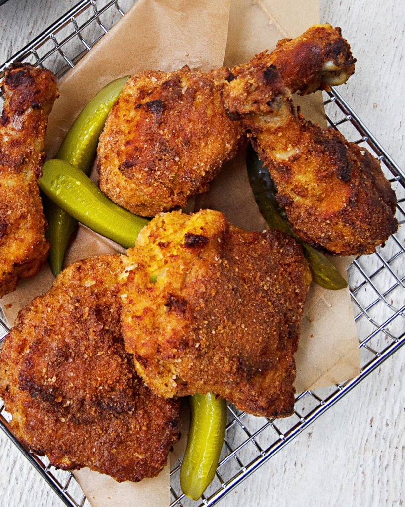 pickle brined fried chicken in a wire basket with pickle spears.