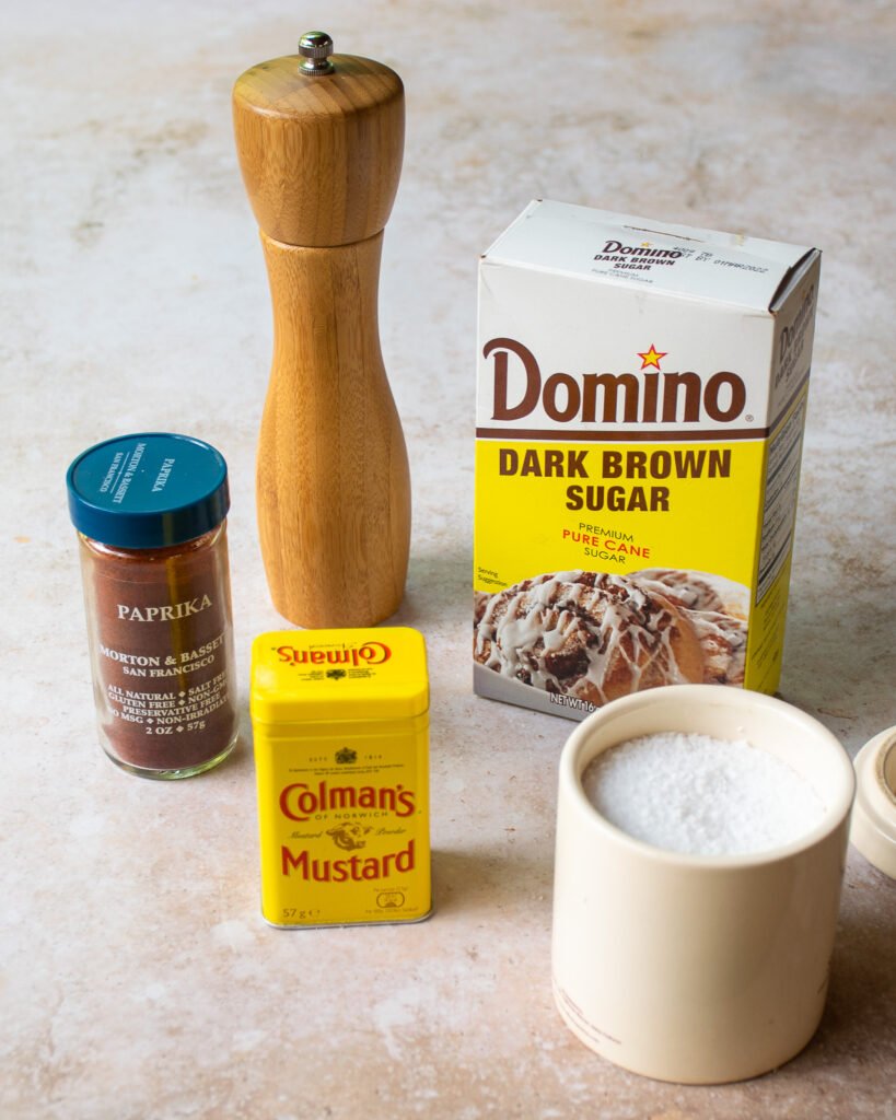 Ingredients on a counter - salt, pepper, dry mustard, paprika and brown sugar.