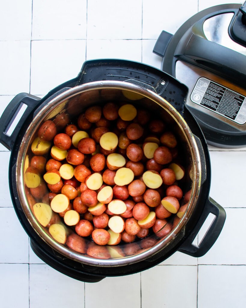 Red baby potatoes in an Instant Pot on a tiled counter.