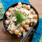 Instant Potato Salad with Lemon Mayo in a black bowl on a wooden table with blue and green napkins.