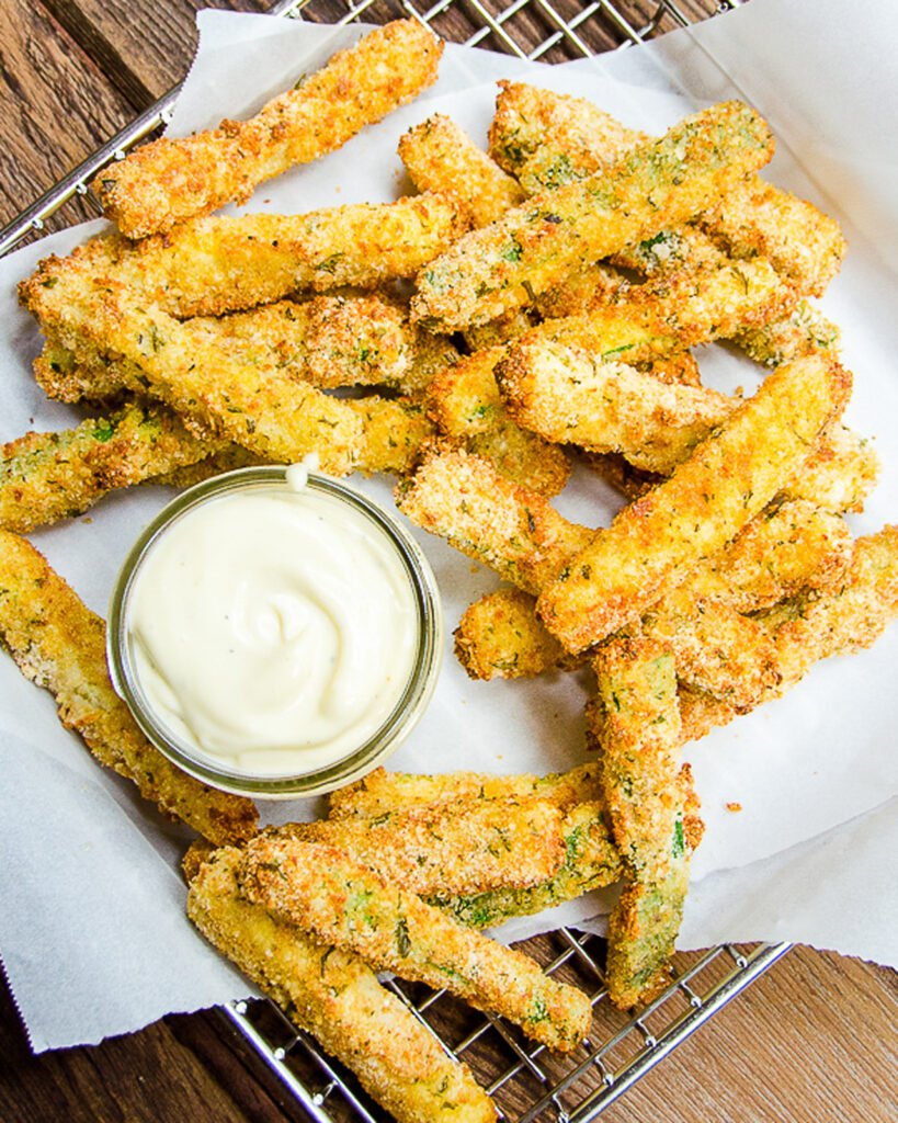 Zucchini Fries on a paper-lined wire basket with a dipping sauce.