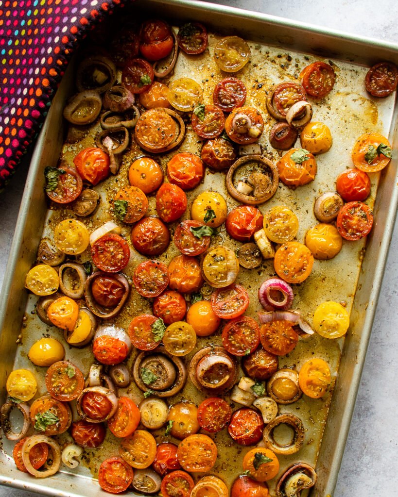 Roasted Cherry Tomatoes on a baking sheet with an oven mitt.