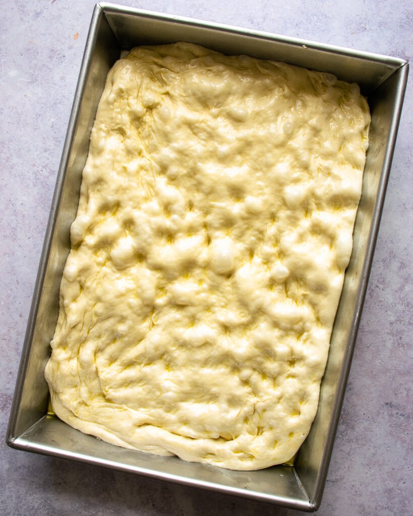 Raw focaccia dough in a 9x13 pan.