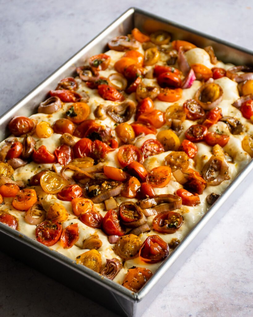 Unbaked roasted cherry tomato focaccia in a baking pan.