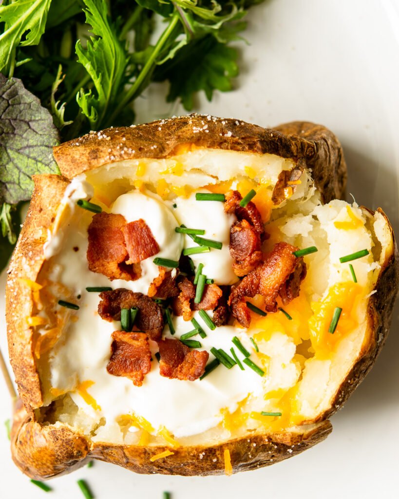Looking straight down into a baked potato with sour cream, Cheddar cheese, bacon and chives.