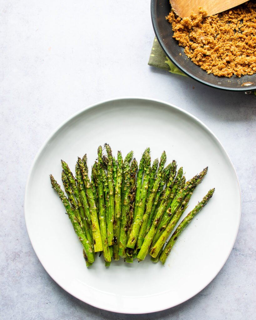 Asparagus spears fanned out on a white plate.