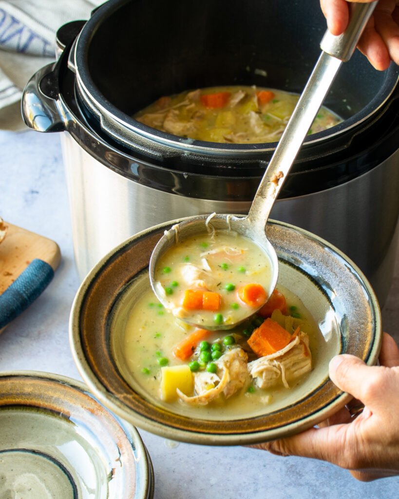 A ladle serving Instant Chicken Stew into a brown bowl.