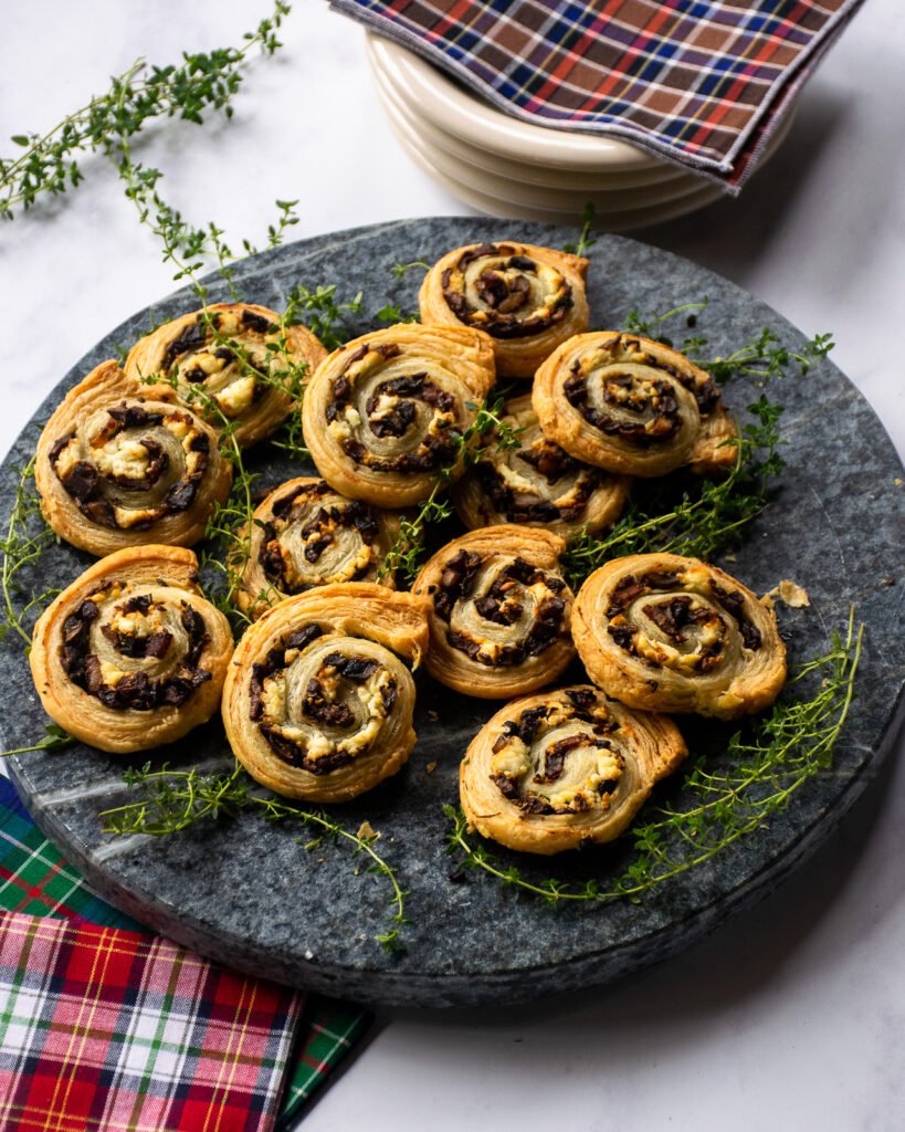 Mushroom goat cheese pinwheels on a tray with plaid napkins around.