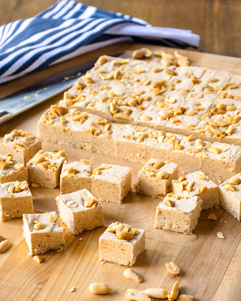 Peanut butter fudge cut into squares on a wooden cutting board.