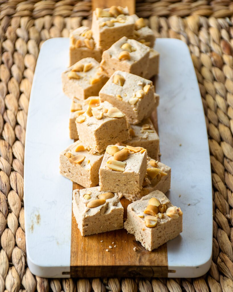 Peanut butter fudge squares on a wood and marble serving board.