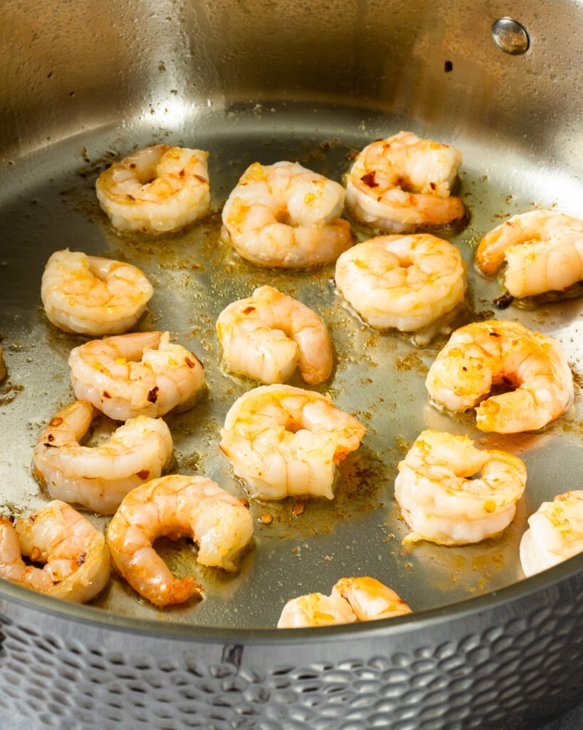 Shrimp seared in a stainless steel pan.