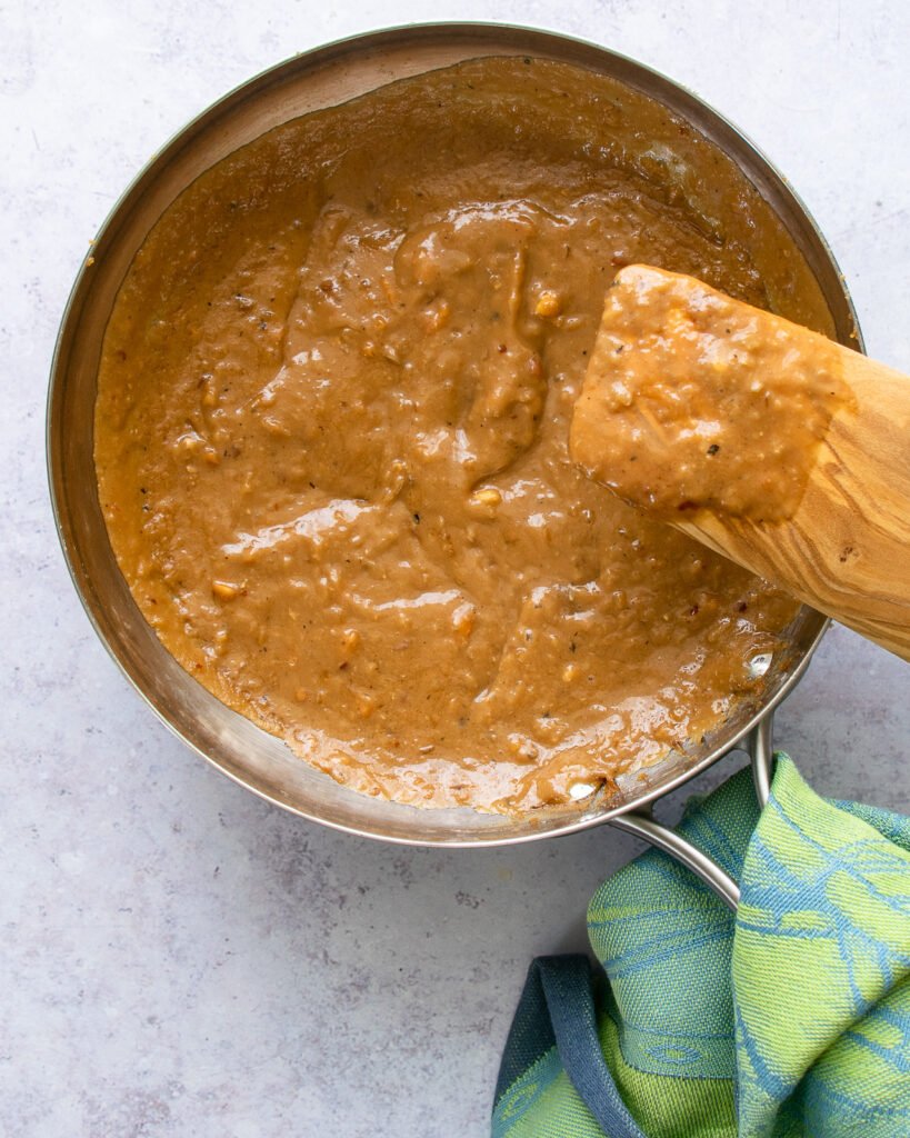 Peanut sauce in a skillet with a wooden spoon.