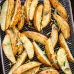 Greek potato wedges on an air fryer basket.