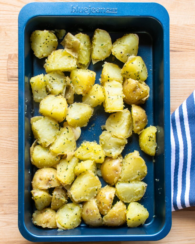 Boiled potatoes in a blue baking pan, ready for the oven.