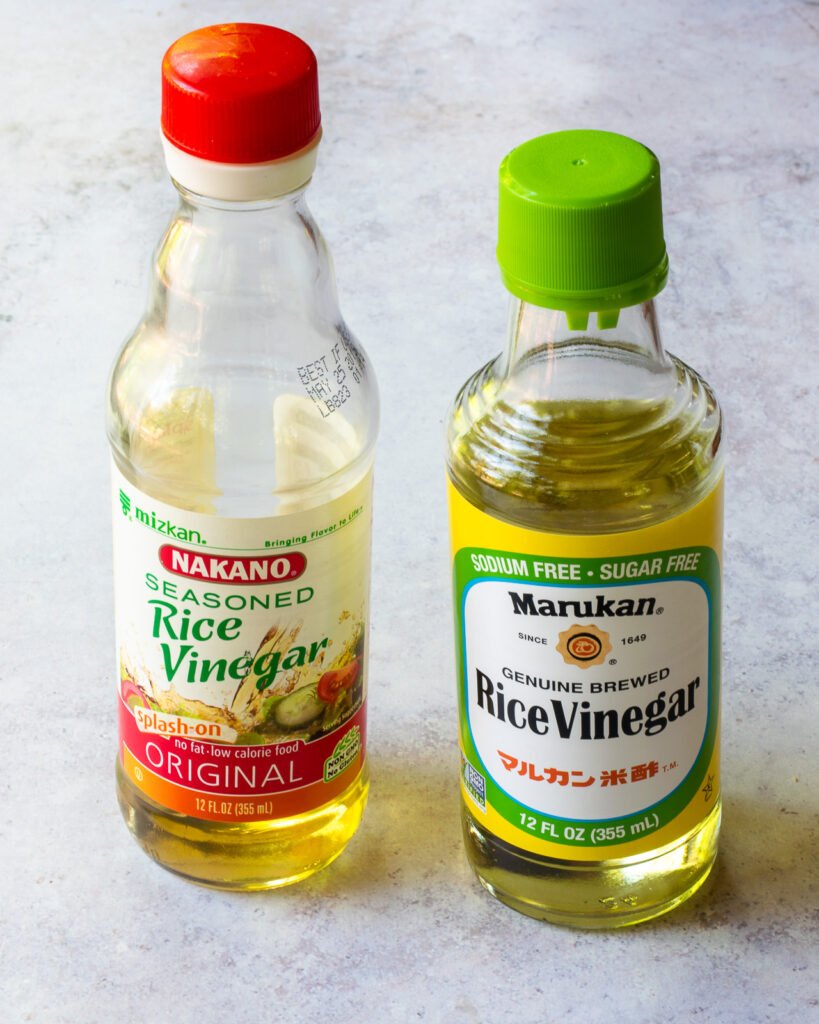 A bottle of seasoned rice vinegar next to a bottle of regular rice vinegar.