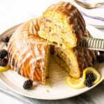Lemon Blackberry Poppy Seed Bundt Cake with a slice being lifted out of the cake.