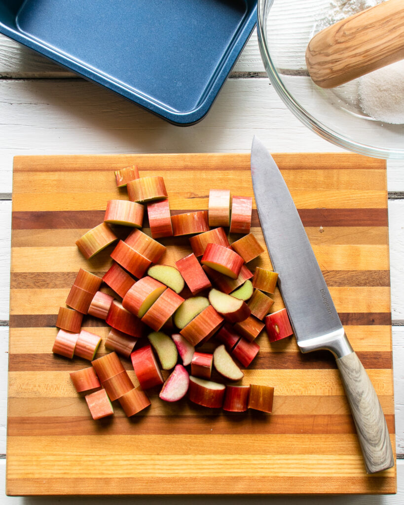 Rhubarb cut into chunks on a wooden cutting board.