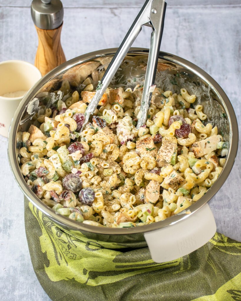 Chicken macaroni Salad in a stainless steel bowl with tongs.