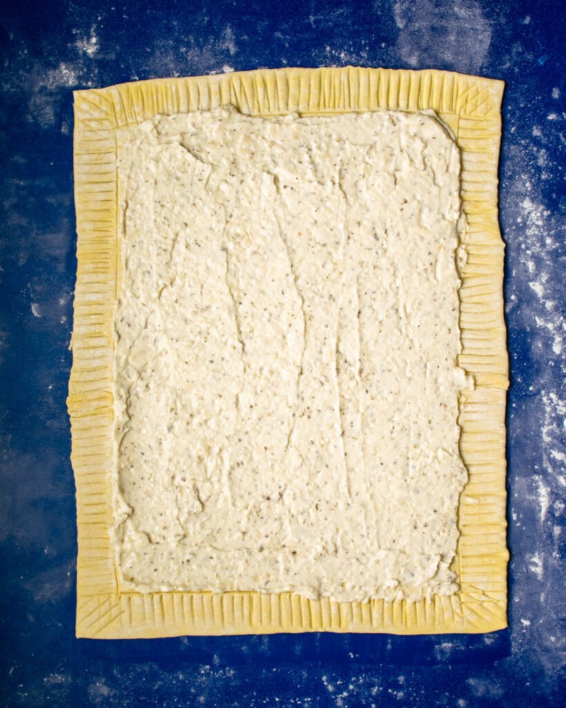 Puff pastry with a mayonnaise spread in the center on a blue background.