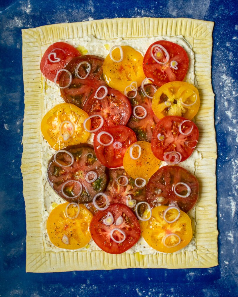 Puff pastry with sliced red and yellow tomatoes on top.