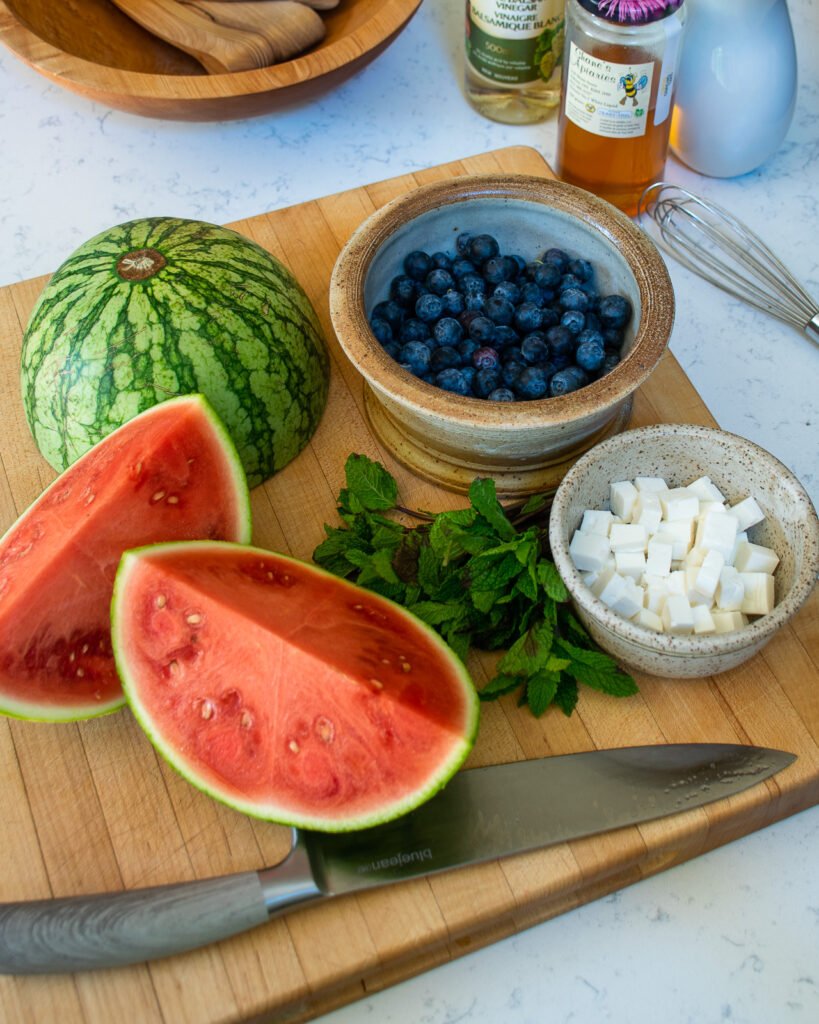 Ingredients on a cutting board - watermelon, blueberries, feta cheese .