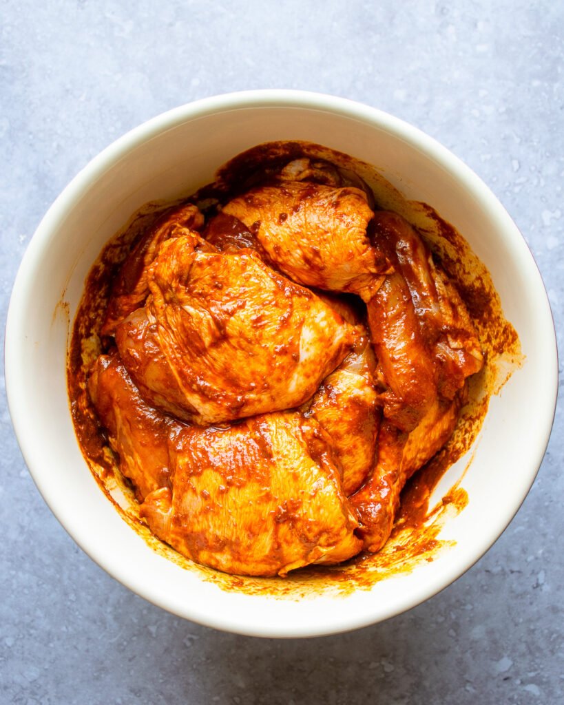 Chicken marinating in a bowl.
