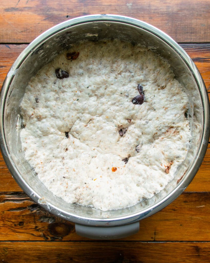 No knead bread dough in a stainless steel bowl after rising for 18 hours.