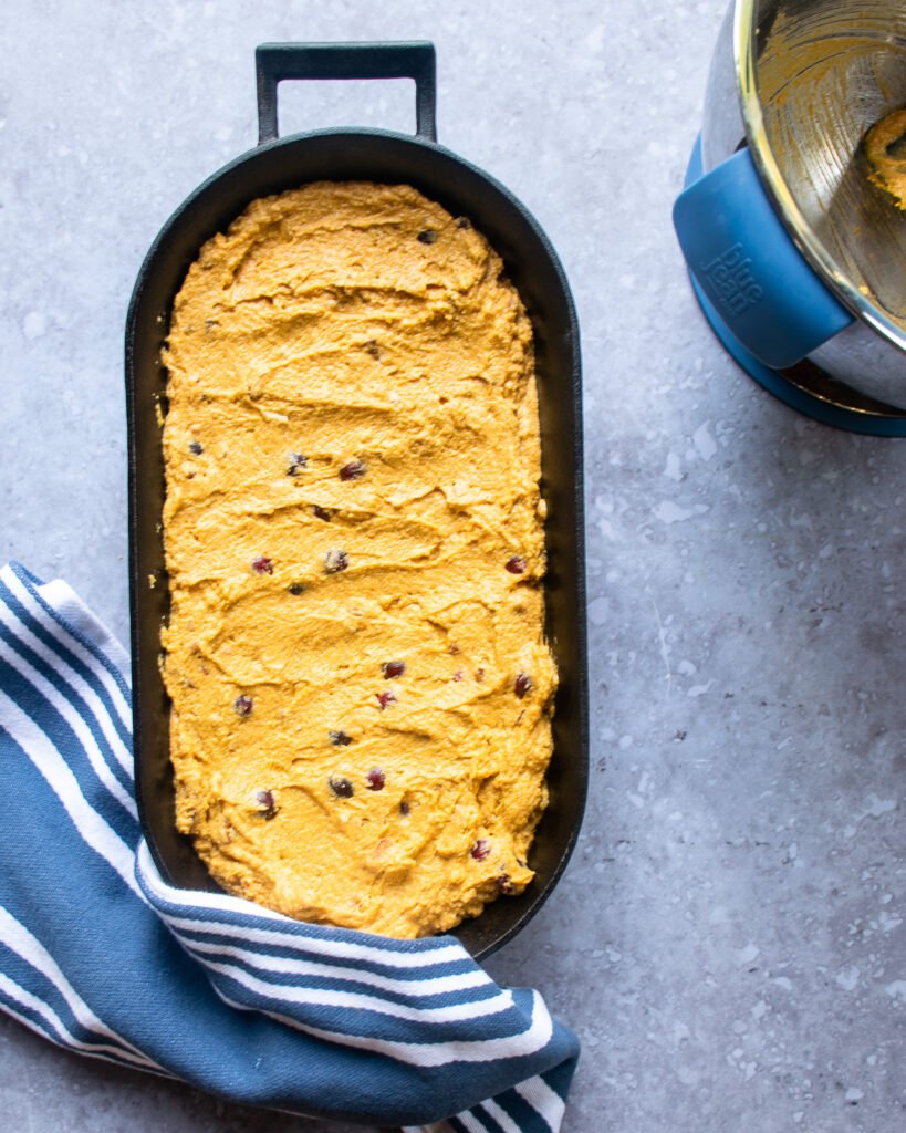 Pumpkin cranberry cornbread batter in an oval cast iron pan before baking.